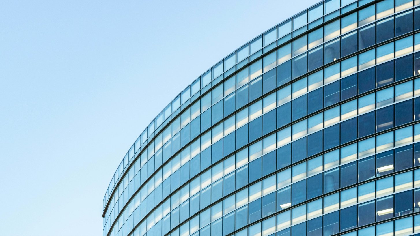 A curved glass office building against a clear sky